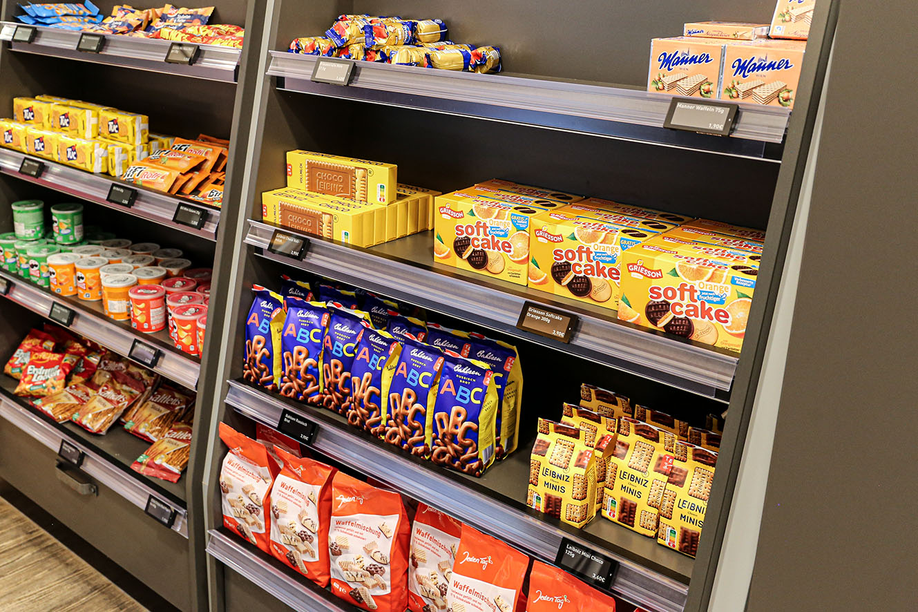 Digitale Preisschilder von Shop-IQ am Süßwarenregal in einer Tankstelle.